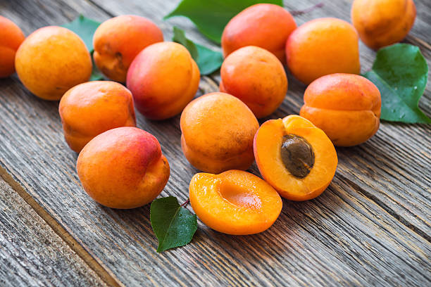 istock Organic apricots with leaves on wooden background 539113320