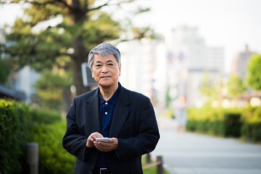 Senior Japanese man using a smart phone in an urban setting