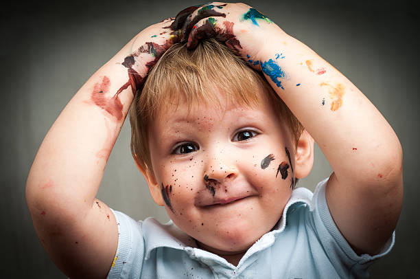 Child himself dirty in paint and looks into camera