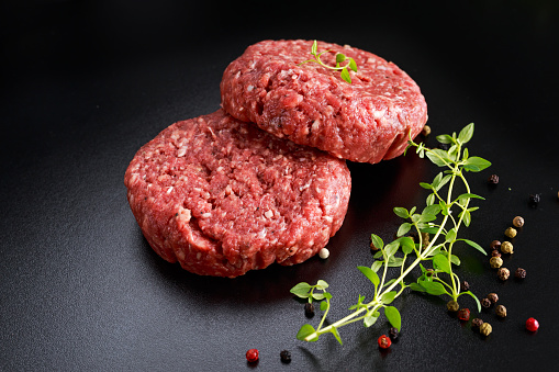 Home HandMade Raw Minced Beef steak burgers on black board.