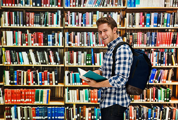 istock Smiling student holding books in library 539121570
