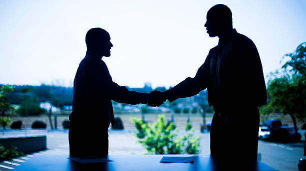 istock Two Businessmen Shaking Hands Silhouette 539121848