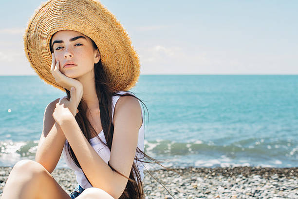 Beautiful woman on sea vacation Beautiful woman sitting on a beach straw hat photos stock pictures, royalty-free photos & images