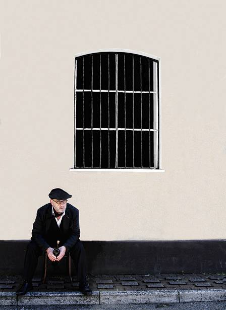 istock man with wine bottle sitting below barred window 539126270