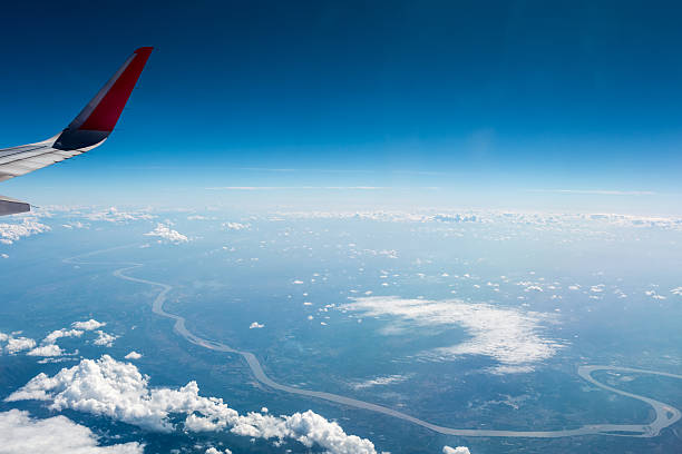 airplane wing above the clouds and winding river , thailand