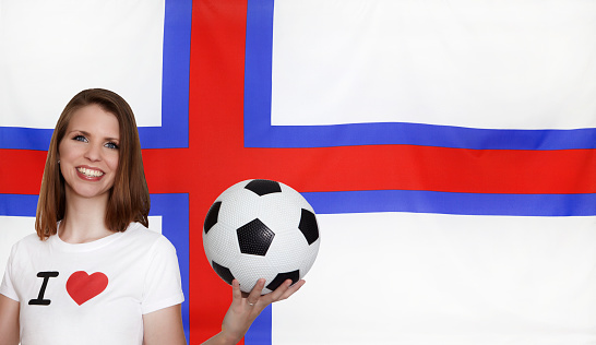 Attractive female soccer fan with textile flag of Faroe Islands seamless close up with wind waves in the real fabric