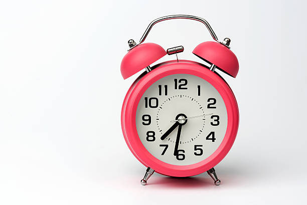 Small red alarm clock on bright pink table. Performance, work or study concept, Creative flatlay copy space above