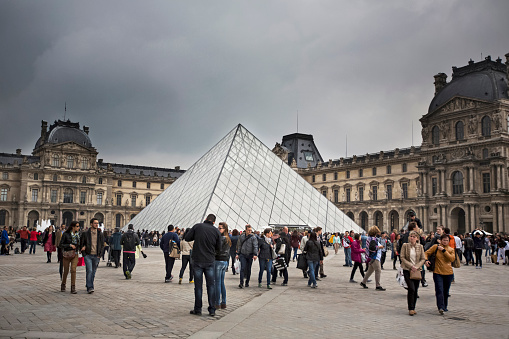 Paris, France - May 2, 2014: Crowd of people around of the Pei’s Pyramid visiting the Museum of Louvre in Paris.