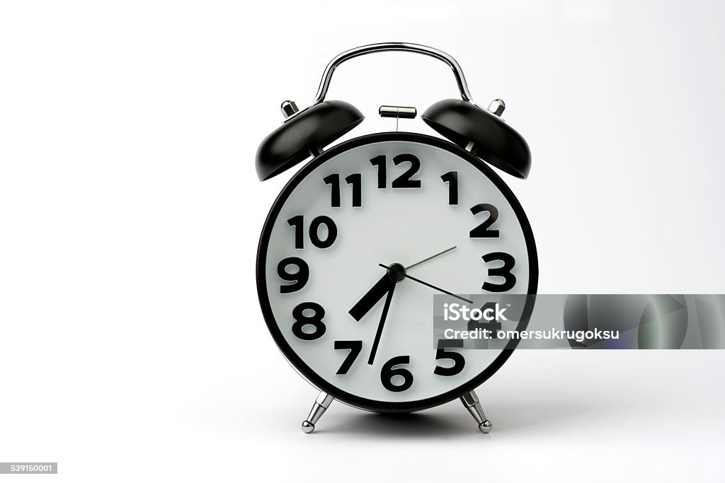 Close-up of Black Table Alarm Clock on White Background Close-up of black colored table alarm clock isolated on white background. Horizontal composition and no people. Selective focus. 12 O'Clock Stock Photo