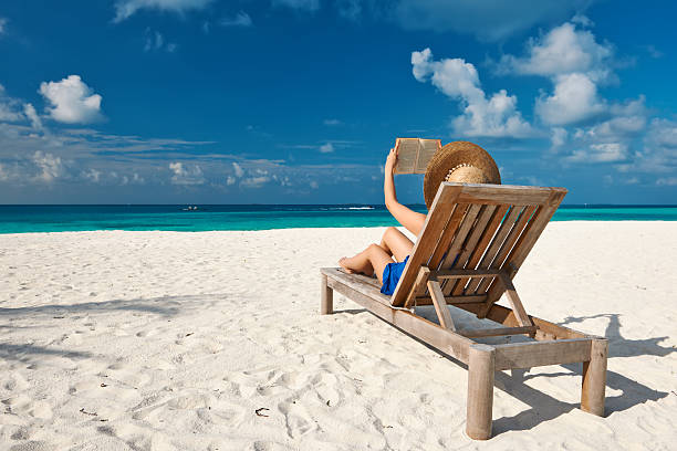 istock Young woman reading a book at beach 539165517
