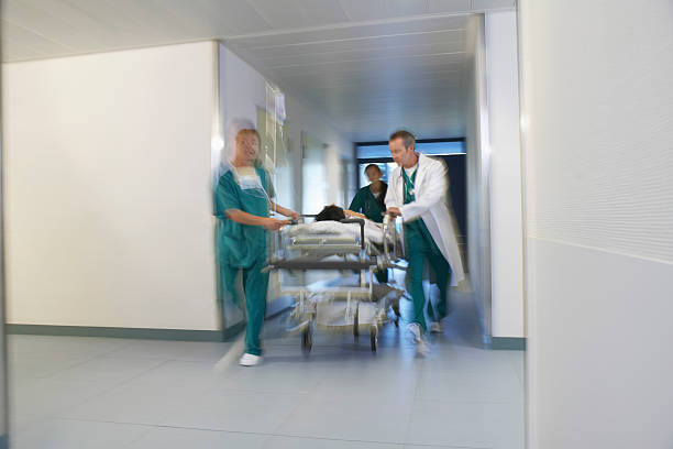 istock Physicians Moving Patient On Gurney Through Hospital Corridor 539166151
