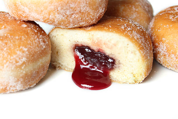 Image of fresh jam doughnuts / jelly donuts, with caster sugar Photo showing some freshly cooked raspberry jam doughnuts (referred to as jelly doughnuts / donuts in the US). The doughnuts have been fried, injected with a generous amount of jelly / jam and then dipped in caster sugar. Jam Doughnut stock pictures, royalty-free photos & images