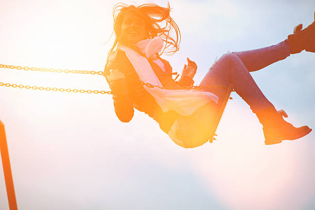 istock Young woman having fun swinging in sunlight 539205617