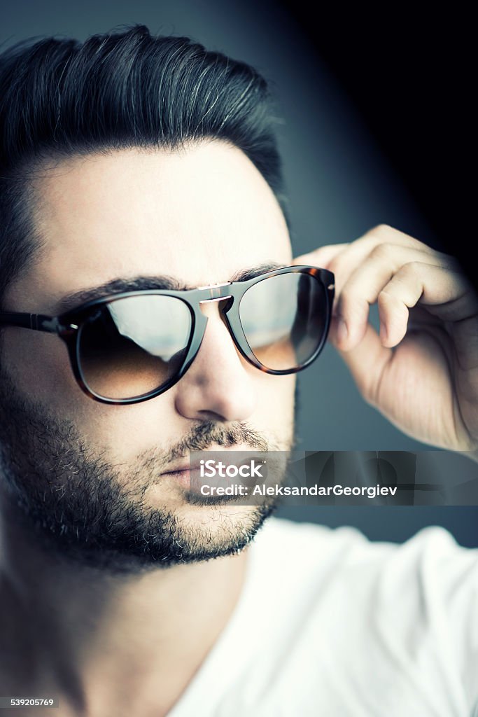 Close up of Good Looking Man with Beard Wearing Sunglasses Close up of Good Looking Man with Beard Wearing Sunglasses. Serious posing with glasses in studio. 20-24 Years Stock Photo