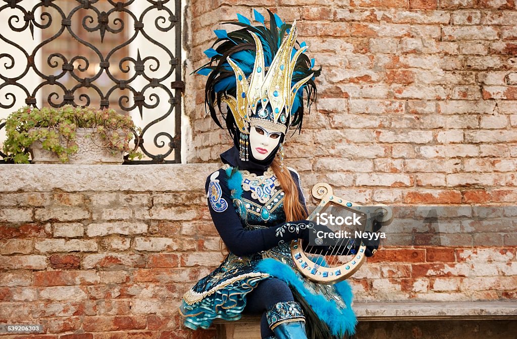 Venice Carnival 2015 The photo was taken during the famous Venice carnival on Campo San Zaccaria. We can see female person in carnival costume who holding lyra instrument. Venice, Italy.  Venice - Italy Stock Photo