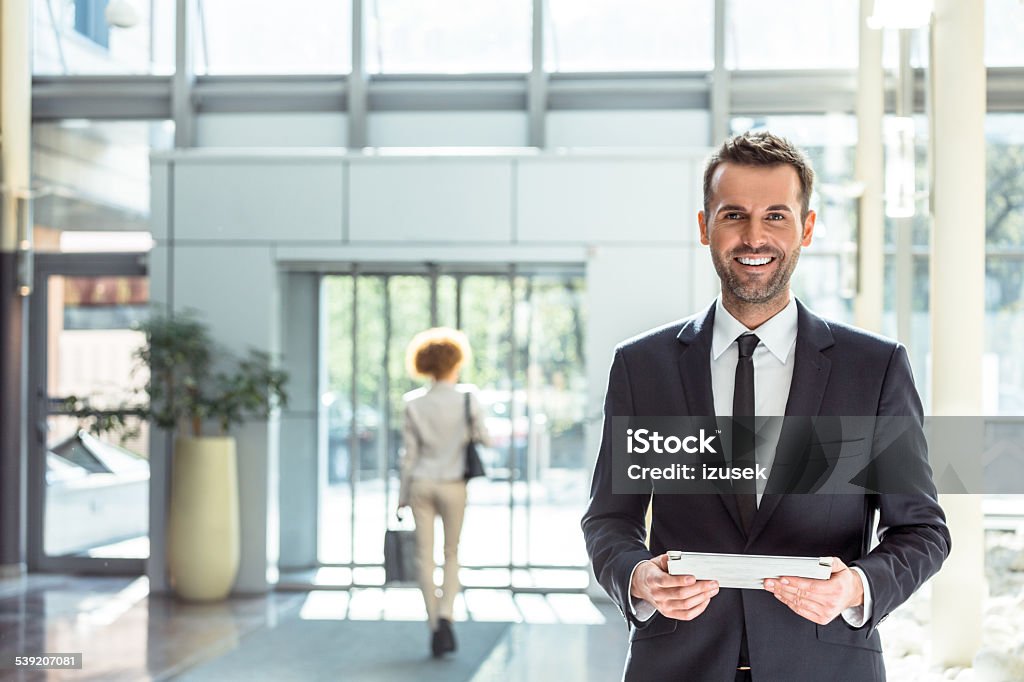 Hotel manager with a digital tablet Portrait of happy businessman standing in hotel hall and holding a digital tablet in hands, smiling at camera.  Hotel Stock Photo