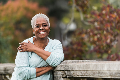 Portrait of a happy, senior African American woman, smiling at the camera, standing in a park.
