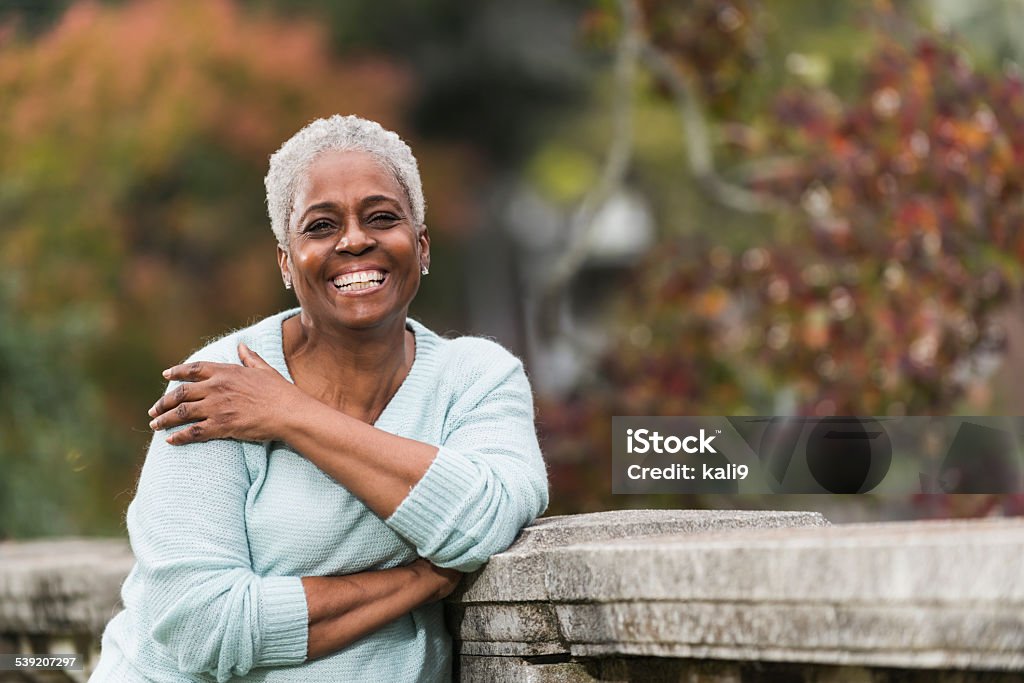 Senior African American woman at the park Portrait of a happy, senior African American woman, smiling at the camera, standing in a park. Senior Adult Stock Photo