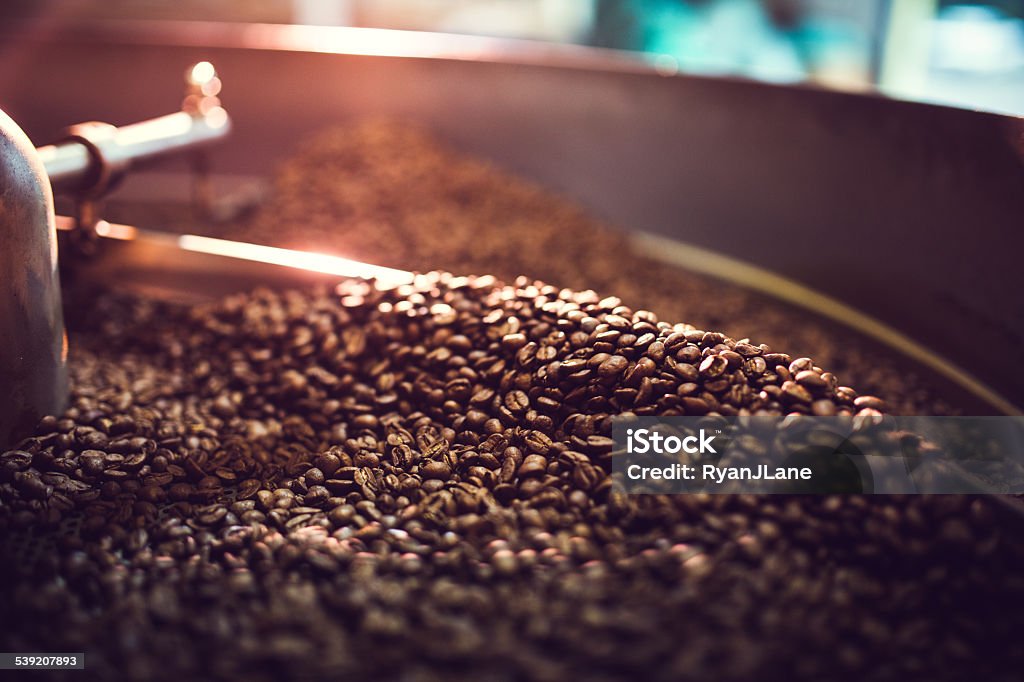 Coffee Roaster Cooling Batch of Beans The process of roasting a batch of high quality single origin coffee beans in a large industrial roaster; the toasted beans are in the cooling cycle.  Horizontal image with copy space.  High contrast with colorful tones. Roasted Coffee Bean Stock Photo