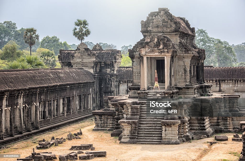 Yoga Retreat, Handsome man doing a Handstand, Angkor Wat Handsome man doing a handstand in front of an ancient temple by the famous Angkor Wat in Cambodia. Nikon D810. Converted from RAW. Cambodia Stock Photo