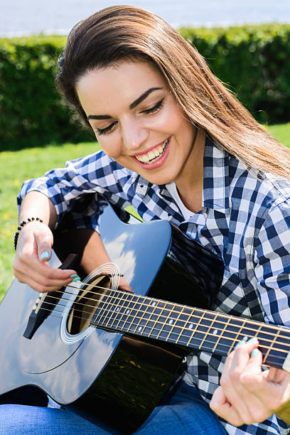istock girl on a green meadow playing guitar 539212024
