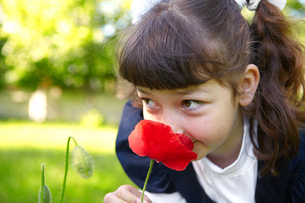 маленькая девочка пахнущие оранжево-красный - child outdoors bow horizontal стоковые фото и изображения