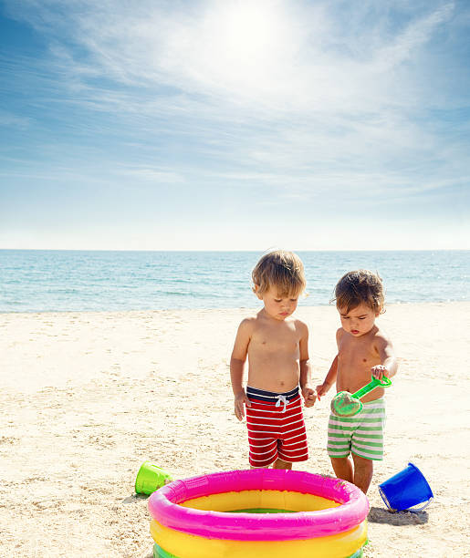 dos niños jugando en la playa - blond hair overcast sun sky fotografías e imágenes de stock