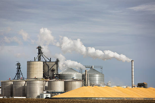 ethanol plant und großen haufen von mais im mittleren westen. - ethanol stock-fotos und bilder