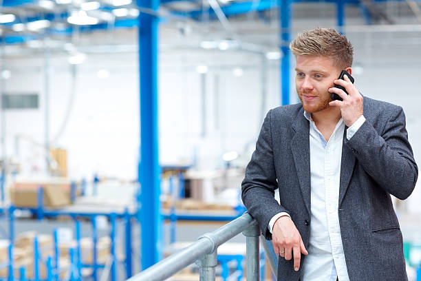 istock Young businessman in factory using mobile phone 539215301