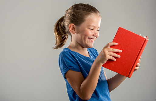 A cute and happy young girl enjoying a book
