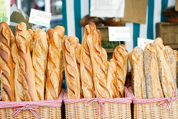 baguettes at the market Paris, France - July 26, 2009: An assortment of freshly-baked baguettes on display in baskets at a farmer's market stall in Paris. bread bakery baguette french culture stock pictures, royalty-free photos & images