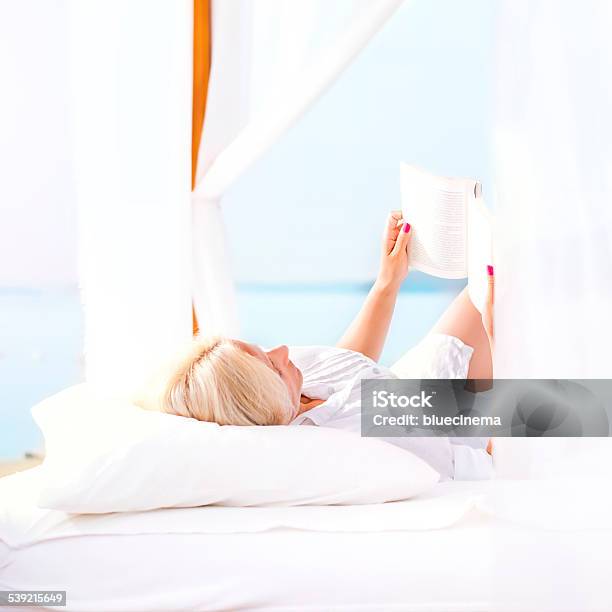 Mujer Leyendo Un Libro En La Playa Foto de stock y más banco de imágenes de 2015 - 2015, Actividades recreativas, Adulto