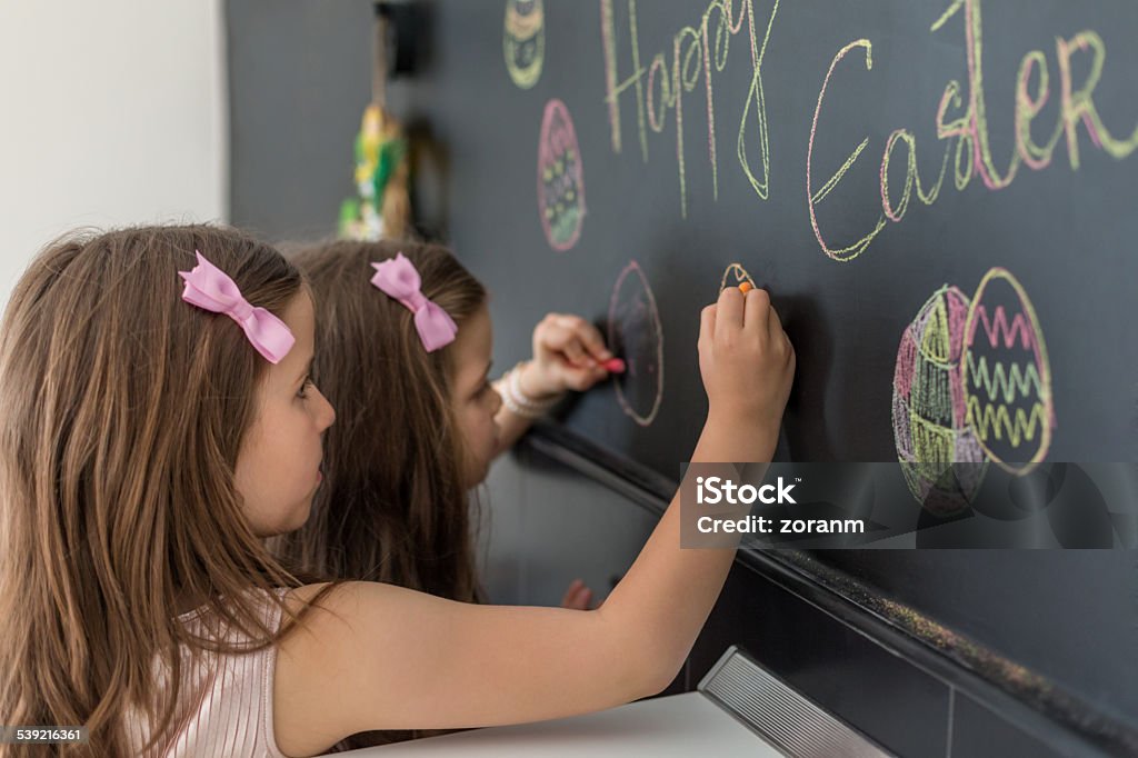 Easter Two cute girls drawing easter eggs on blackboard Child Stock Photo