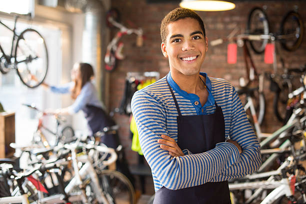 it's a great place to work bike shop worker stands proudly in front of his stock first job photos stock pictures, royalty-free photos & images