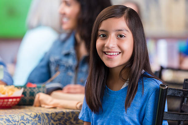 Elementary age Hispanic girl in Tex-Mex restaurant with family Elementary age Hispanic girl in Tex-Mex restaurant with family mex mexican restaurant tex stock pictures, royalty-free photos & images