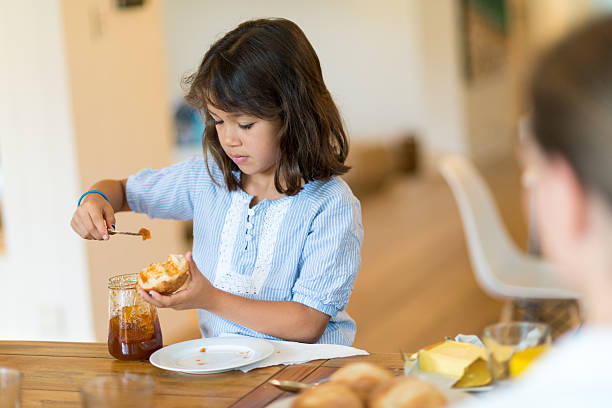 Girl putting marmalade on the bread