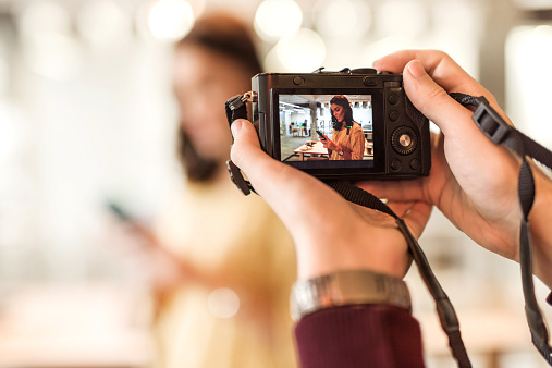 Unrecognizable man taking a photo of a young woman.