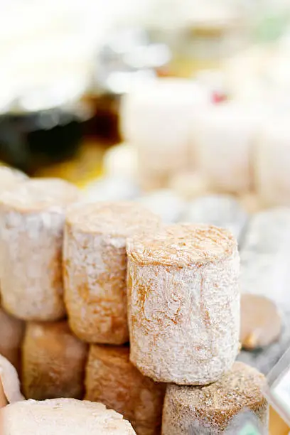 Stacks of artisan goat and other cheeses on display at a farmer's market in Paris.
