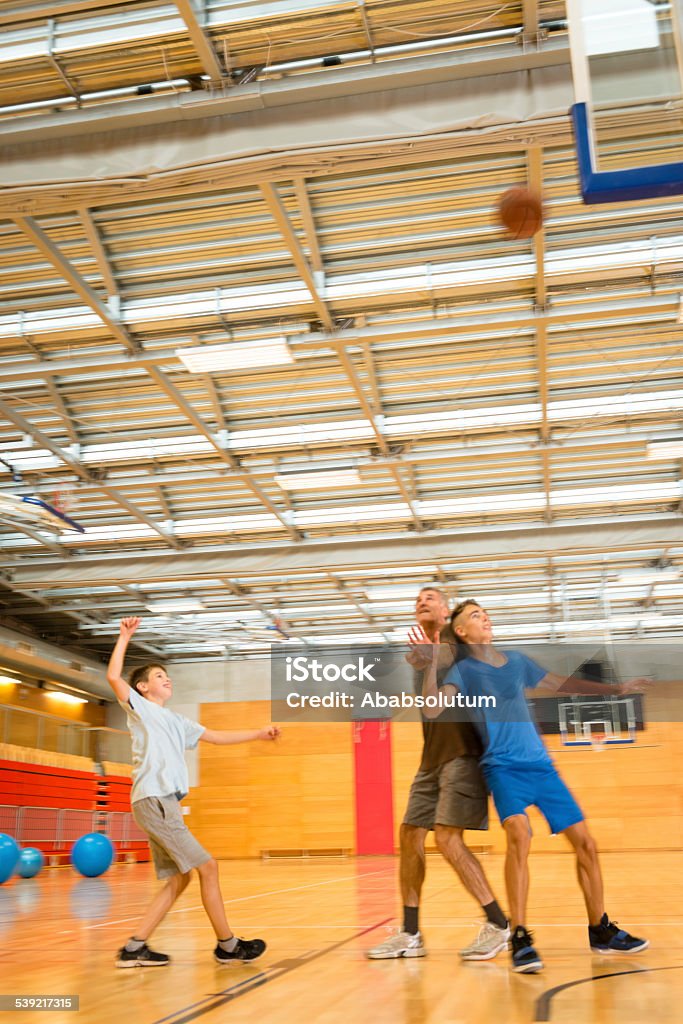 Padre y dos niños jugando al básquetbol, Sportshall, Eslovenia, Europa - Foto de stock de Gimnasio escolar libre de derechos