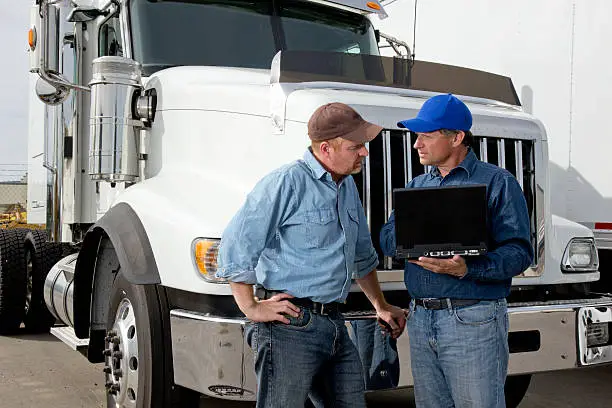 A royalty free image from the transportaion industry of two truck drivers using a laptop computer at a truckstop.