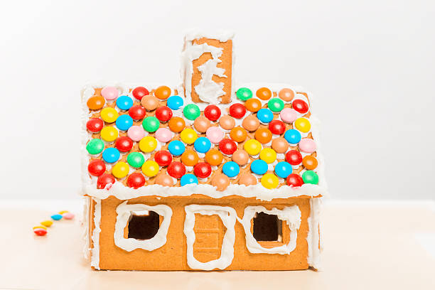 A handmade decorated gingerbread Christmas house photographed against a white background with Christmas lights.Suitable for a background or a Christmas card with a message.