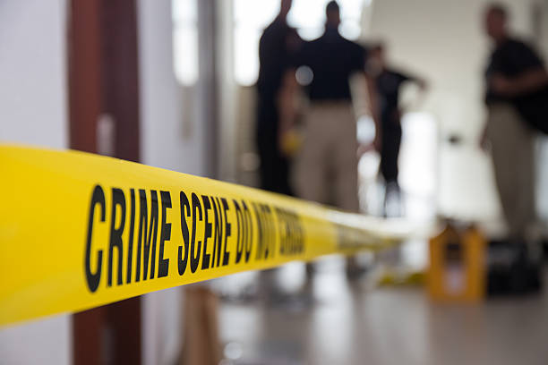crime scene tape in building with blurred forensic team stock photo