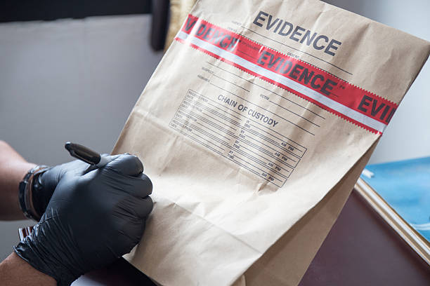 hand in glove writing on sealed evidence bag forensic 's hand in black glove writing on evidence bag and seal by red tape in crime scene investigation forensic science stock pictures, royalty-free photos & images