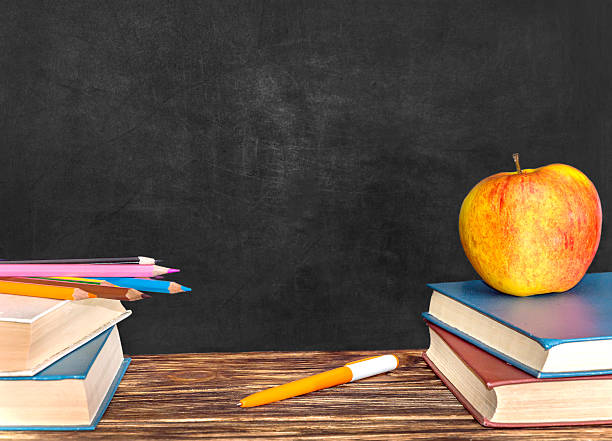 istock Books, colored pencils, pen and apple at blackboard background 539230304