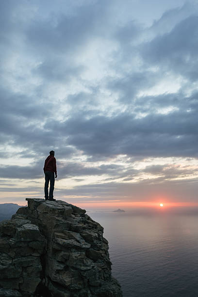 istock Man looks at the seascape from a cliff 539233483