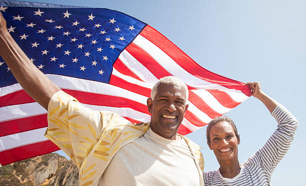 senior coppia afro-americana di trasporto bandiera usa - women african descent old american culture foto e immagini stock