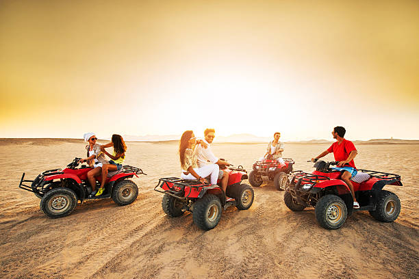 gruppo di giovani guidano quad moto al tramonto. - off road vehicle quadbike desert dirt road foto e immagini stock