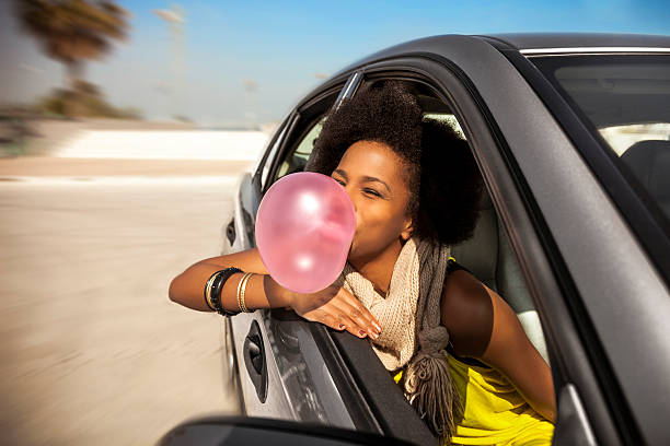 mujer jugando con goma de mascar en un viaje por carretera - chewing gum women bubble blowing fotografías e imágenes de stock