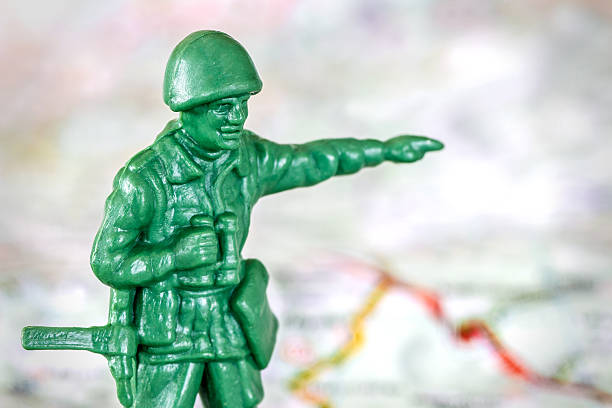 Concept of leadership, with little green soldier toy aiming the way forward, teamwork, in selective focus, placed on a military map. Macro shot.