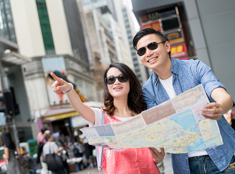 Happy Asian couple sightseeing in Hong Kong and looking at a map